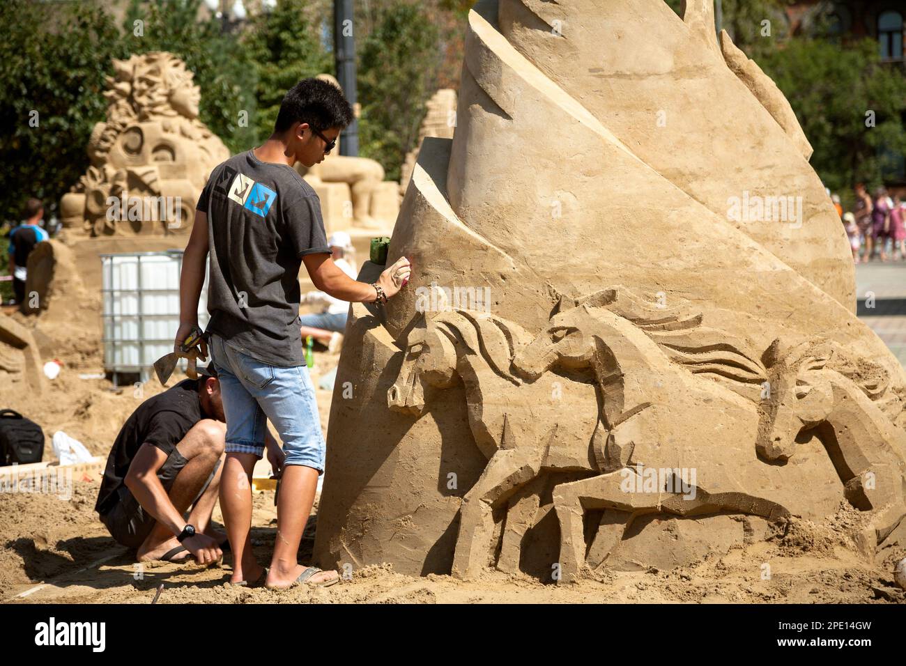 Khabarowsk, Russland - 30. August 2014: Sandskulpturenfestival - zwei junge Künstler, die an einer Pferdefigur arbeiten. Kunstwettbewerb am Strand im Freien Stockfoto