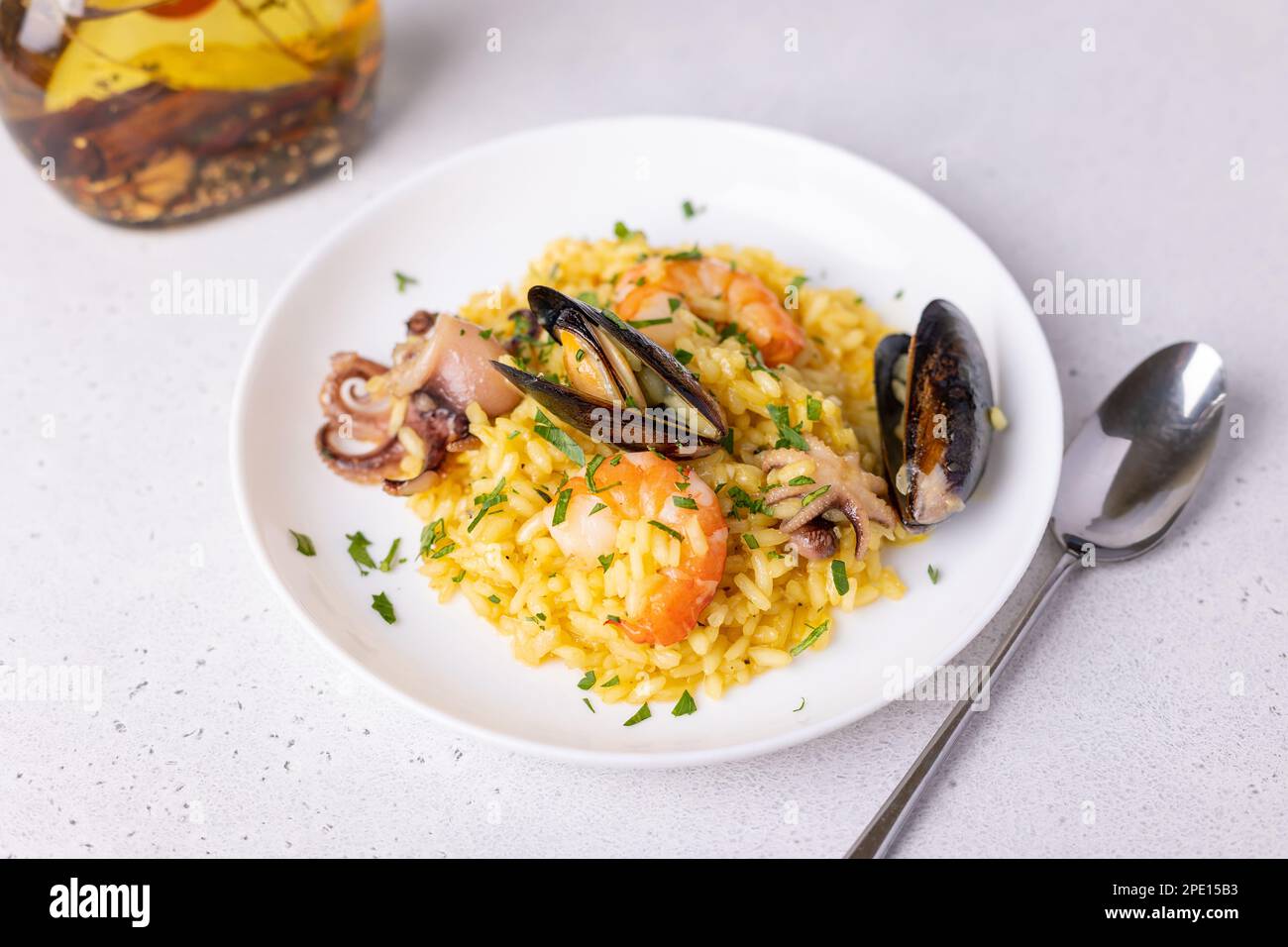 Risotto mit Meeresfrüchten mit Safran und Petersilie. Arborio-Reis mit Garnelen, Muscheln und Babykrake. Traditionelles italienisches Gericht. Nahaufnahme, selektiver Fokus Stockfoto