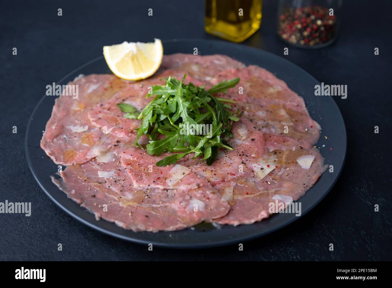 Marmorfleisch-Carpaccio mit Rucola, Parmesankäse, Olivenöl und Zitrone. Eine traditionelle klassische Vorspeise aus dünn geschnittenem rohem Fleisch. Nahaufnahme. Stockfoto