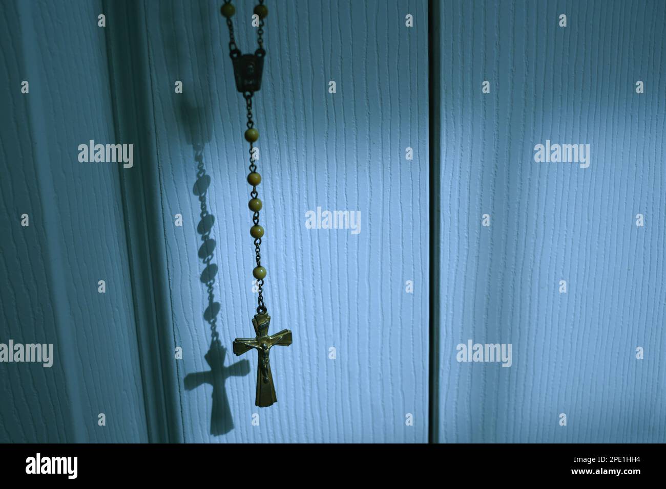 Katholische Kruzifixanhänger und Schranktür im sanften Mondlicht Stockfoto