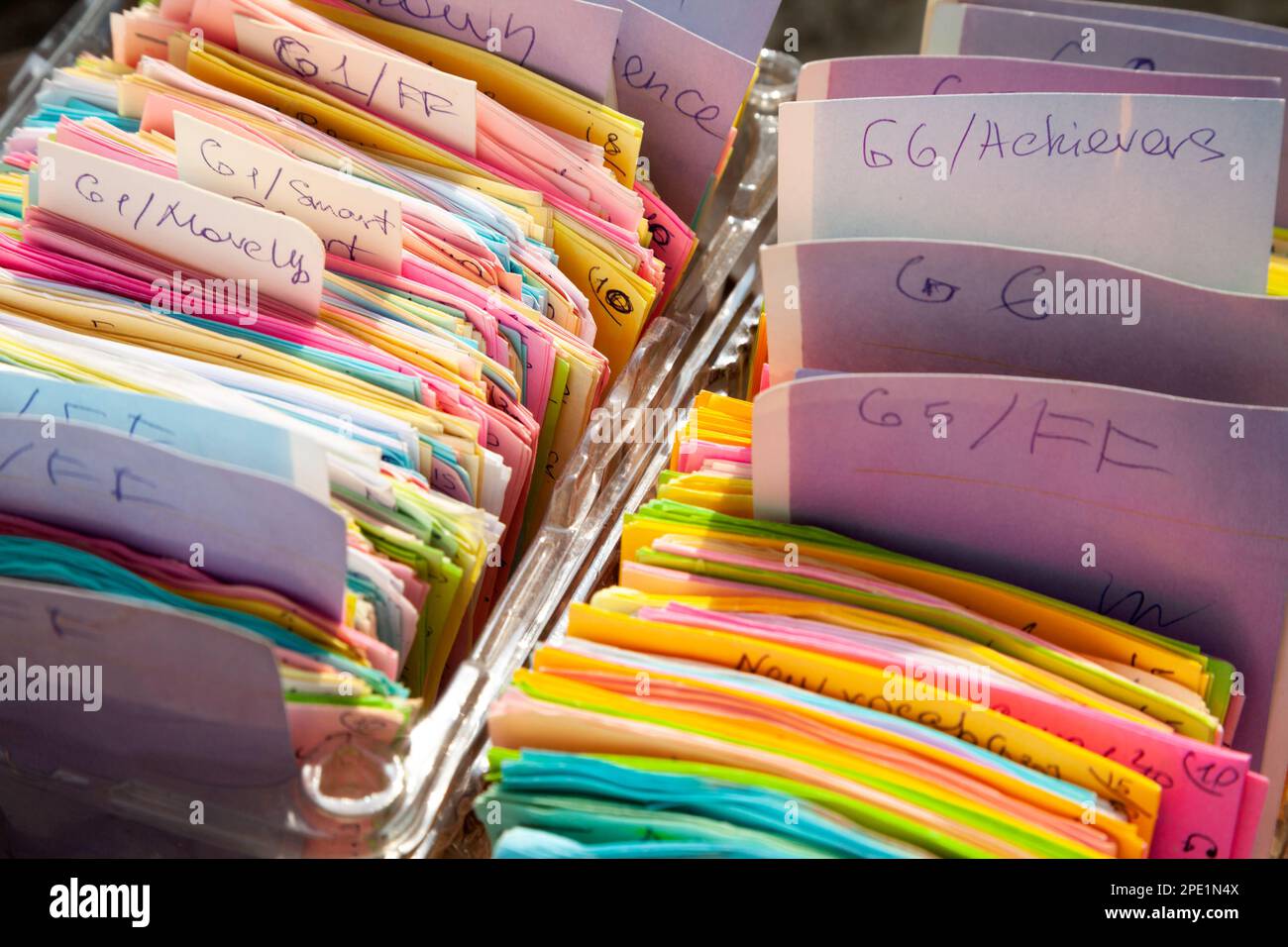 Eine farbenfrohe Karteikarte, die in Reihen angeordnet und in Kartons aufbewahrt wird. Notizen handgeschrieben auf quadratischem Memopapier und kategorisiert Stockfoto