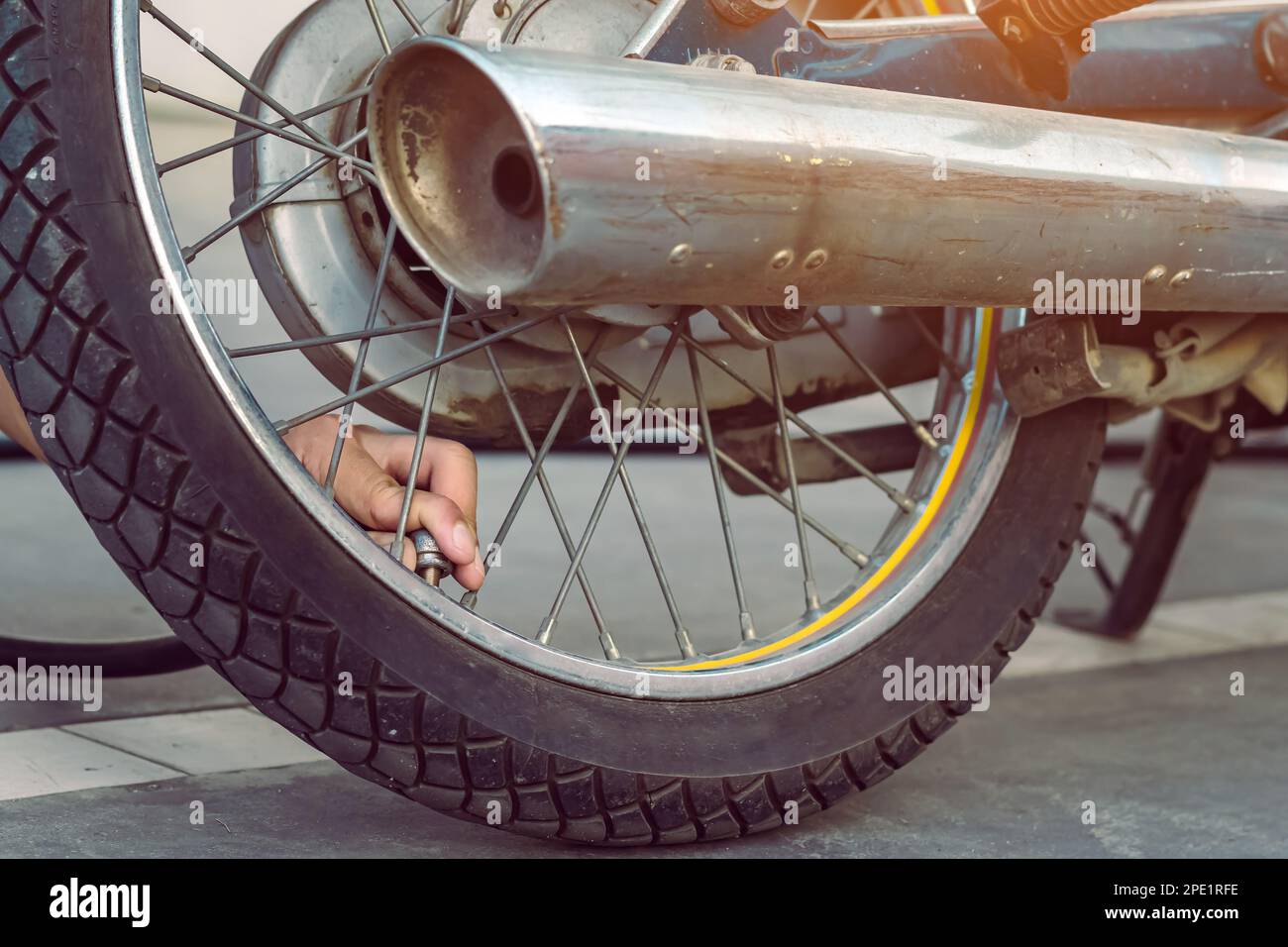 Die Hand eines Mannes prüft den Druck im Gasgenerator und pumpt einen Reifen auf einem Motorrad mit einem Luftkompressor auf. Mann, der den Luftdruck prüft und den Reifendruck auffüllt Stockfoto