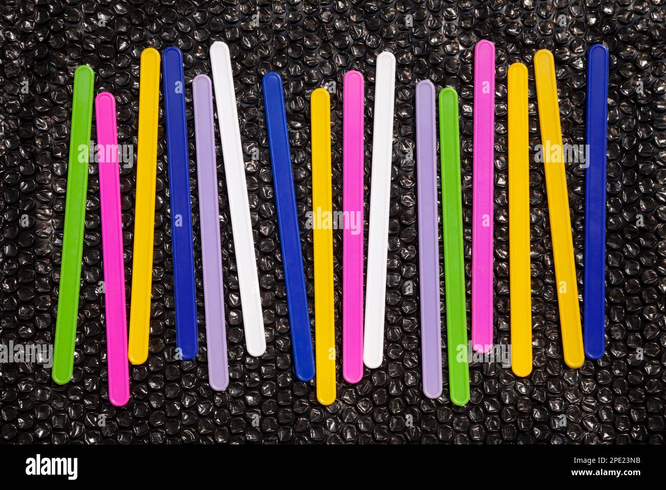 16 farbenfrohe Linien auf schwarzem, abstraktem geometrischem Hintergrund. Plastikzählstäbchen, Zahlenlernhilfe für Kinder Stockfoto