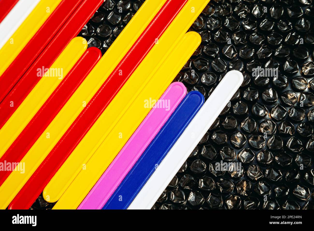 Farbenfrohe Linien auf schwarzem, abstraktem geometrischem Hintergrund. Plastikzählstäbchen, Zahlenlernhilfe für Kinder Stockfoto