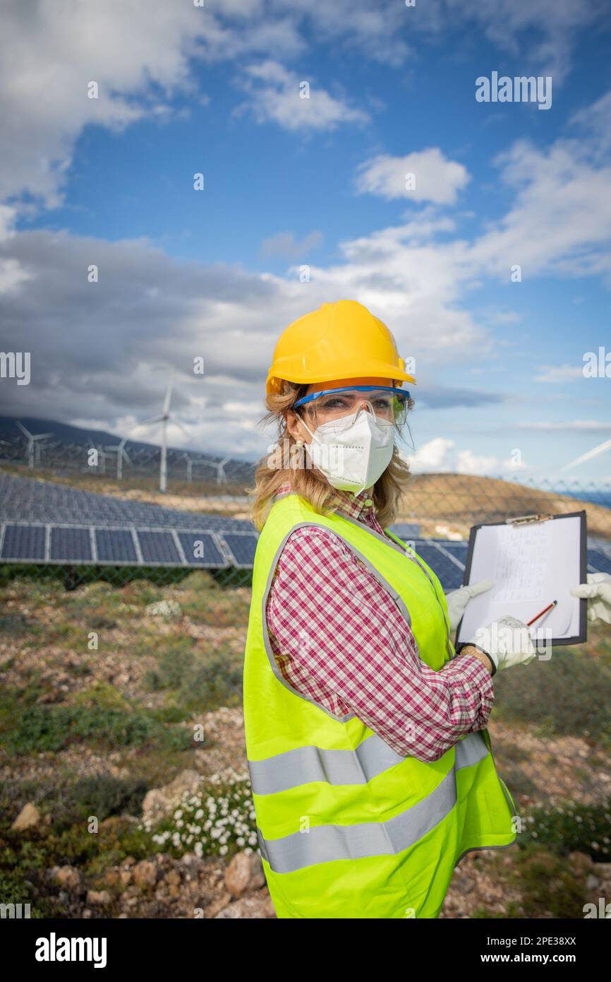 Eine Ingenieurin in einem Solarkraftwerk trägt während der Arbeit schützende Arbeitskleidung. Stockfoto