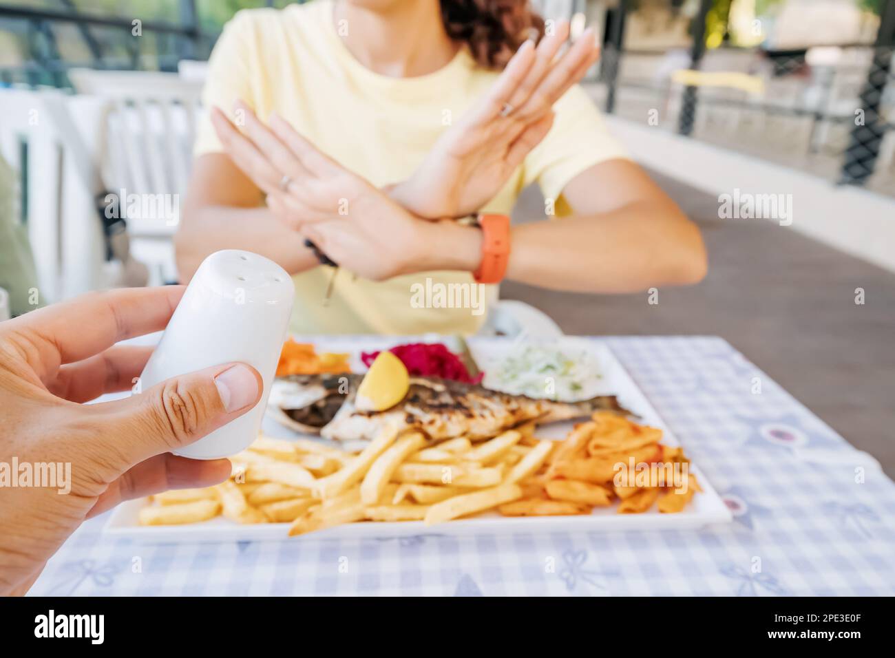 Die Frau weigert sich, ihr Gericht im Restaurant mit einer Geste Nein zu salzen.ein überreicher Verzehr dieser Würze kann zu Kardiovas führen Stockfoto