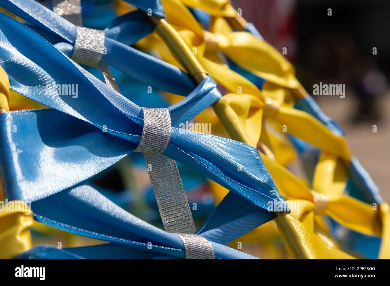 Gelb-blau, Farben der ukrainischen Nationalflagge, Stoffband am Rahmen verflochten. Symbol der Feier der Unabhängigkeit der Ukraine. Stockfoto