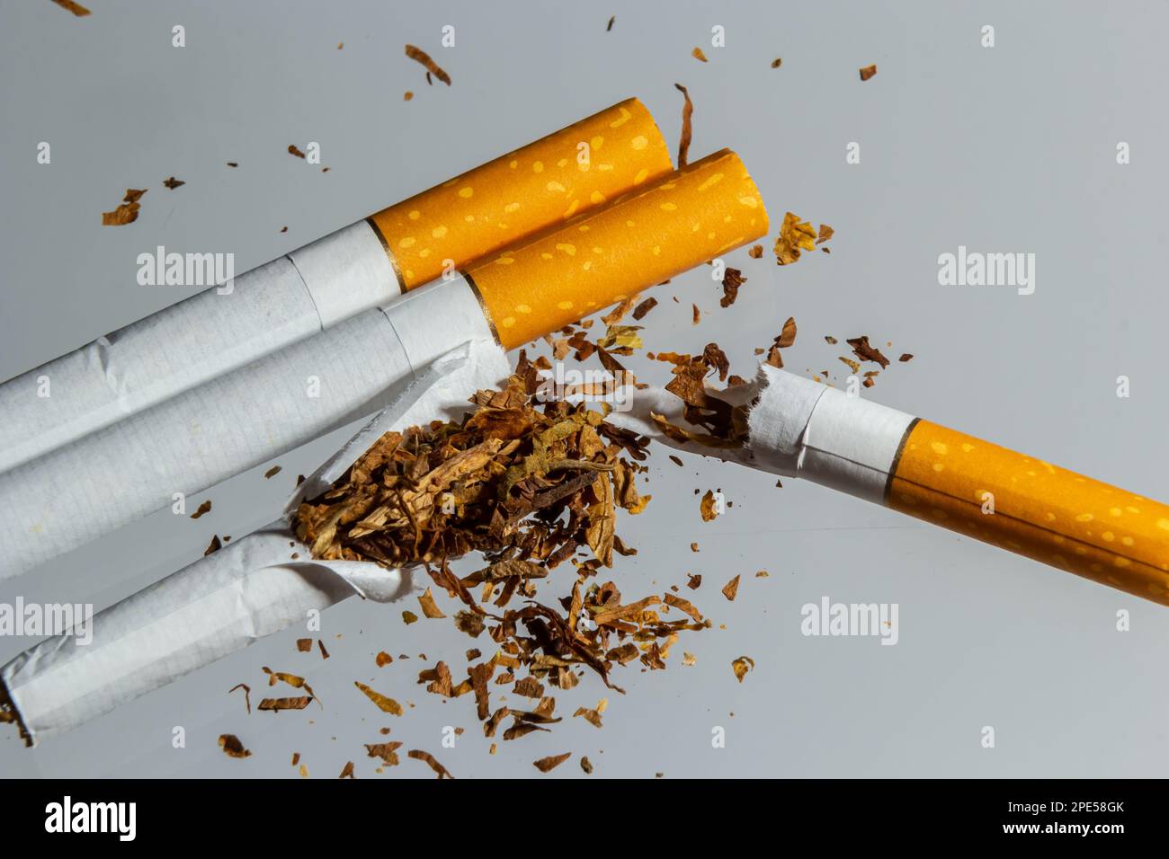 Gebrochene Zigarettenfliege in der Luft auf einem hellen Hintergrund. Konzeption der Bekämpfung des Rauchens. Stockfoto