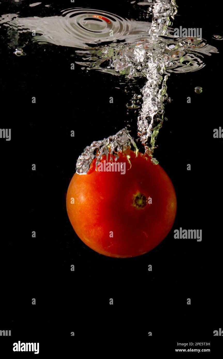 Reife Tomate fällt tief unter Wasser mit einem big Splash. Stockfoto