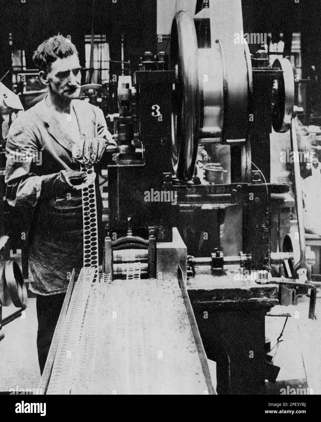 Royal Mint, Tower Hill, London, c1933. Ein Arbeiter überwacht die Maschine, die die leeren Discs stanzt, die zu Münzen werden. Stockfoto