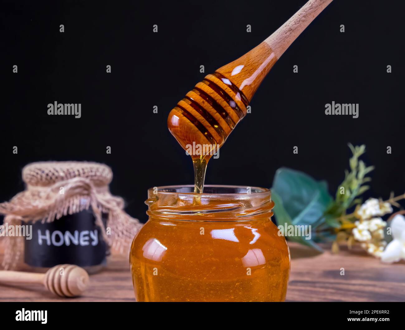 Honiglöffel, der in Zeitlupe aus dem Glas mit Honig kommt. Honig enthält viele Nährstoffe, Antioxidantien, verbessert die Gesundheit des Herzens, Wundversorgung, Angebote Stockfoto