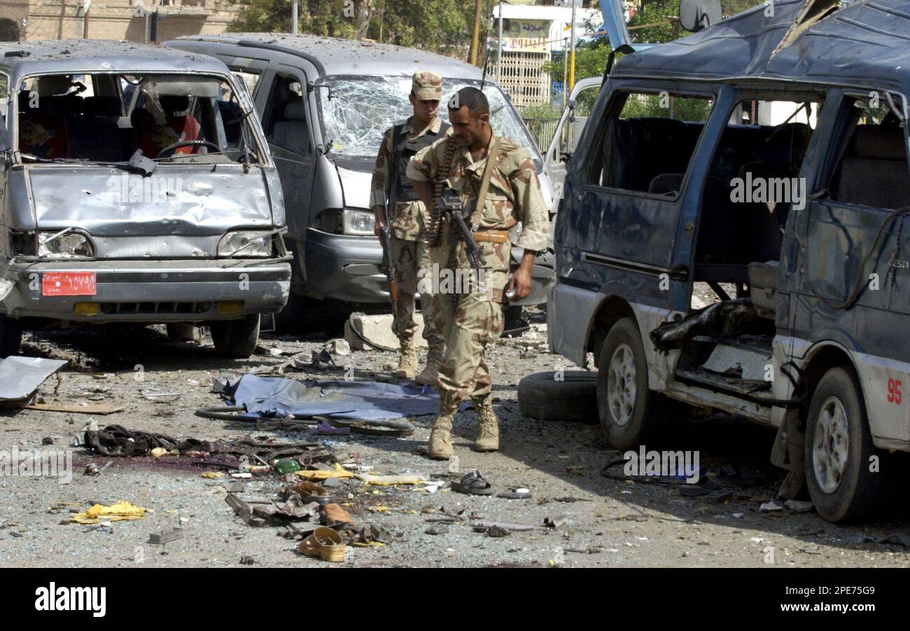 Iraqi soldiers examine wreckages of cars that were destroyed in a car