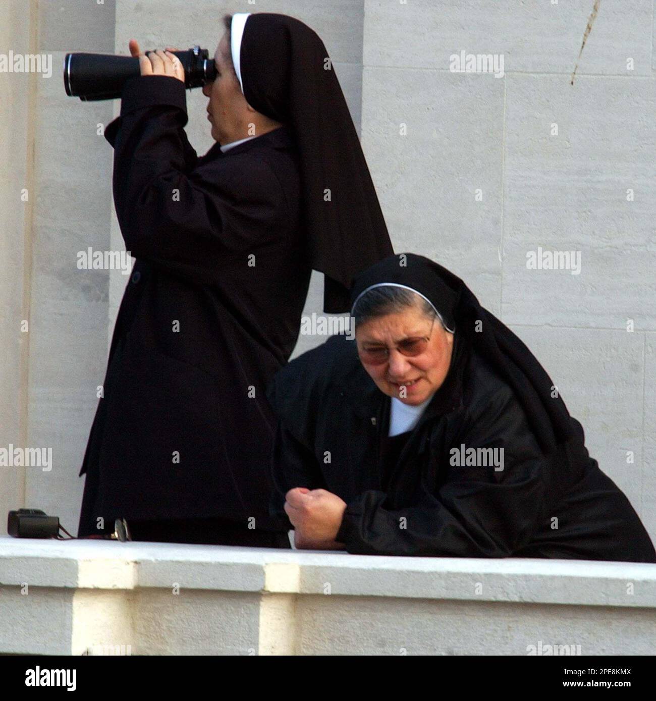 A nun with binoculars and her fellow sister look at pilgrims as they begin to fill St. Peter's Square at the Vatican, where the funeral of Pope John Paul II is to take place, Friday April 8, 2005. Royalty, political power brokers and multitudes of the faithful will pay their last respects to Pope at a funeral promising to be one of the largest Western religious gatherings of modern times. (AP Photo/Gregorio Borgia) Stockfoto