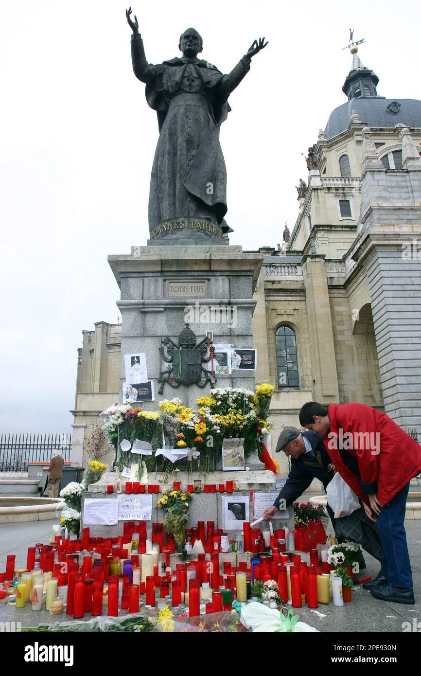 Two men place candles at a makeshift shrine at the foot of a staue of Pope John Paul II outside the Almudena Cathedral in Madrid, Sunday April 3, 2005. The Polish pontiff who led the Roman Catholic Church for more than a quarter century died at the age of 84 on Saturday evening, April 2, at the Vatican. (Manu Fernandez) ** EFE OUT ** Stockfoto