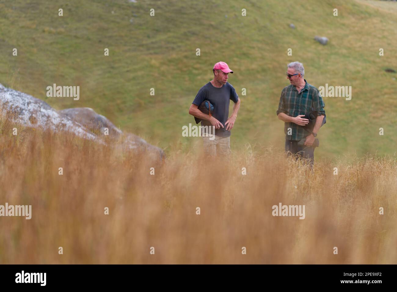 Zwei Leute, die sich in der Ferne unterhalten, auf einem Tagesspaziergang durch Hügel, Castle Hill, Neuseeland. Stockfoto