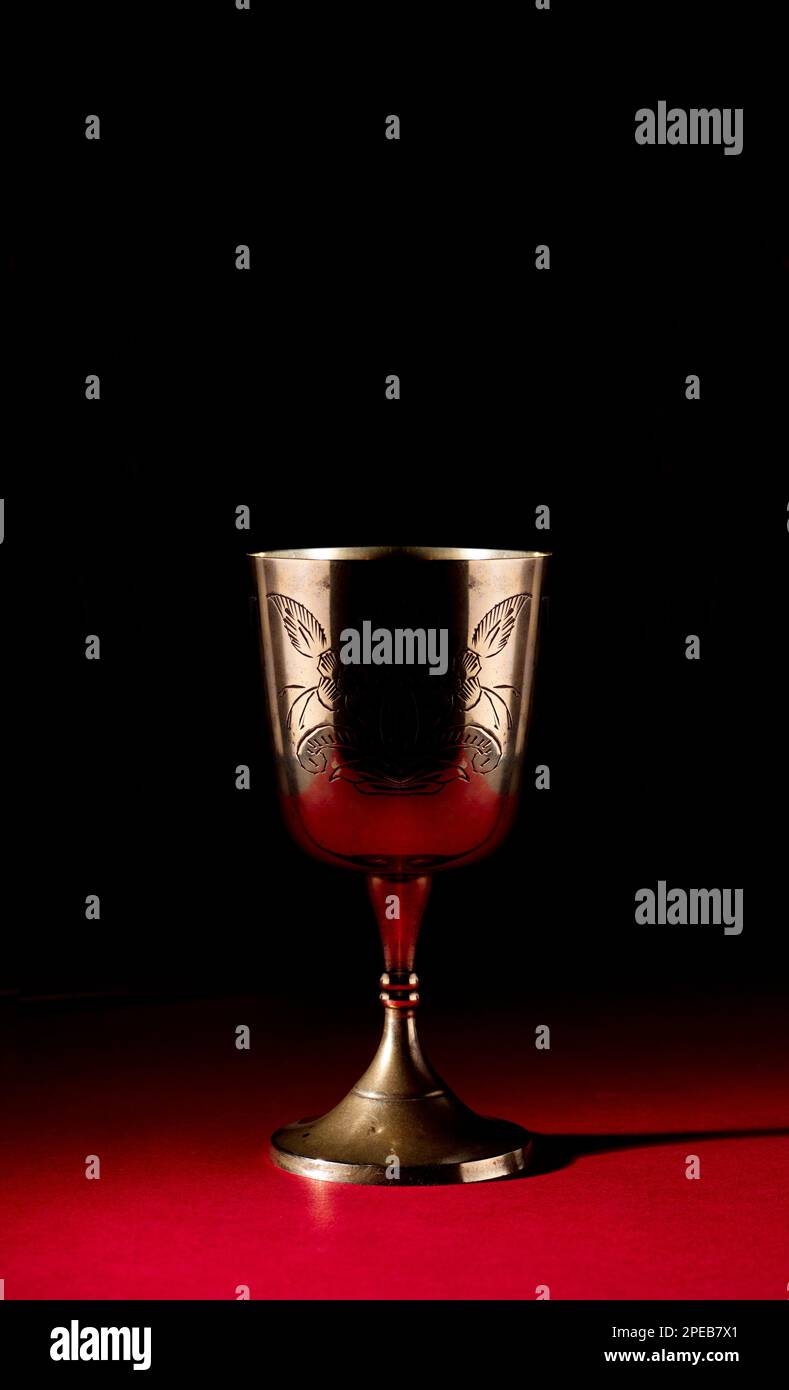 goldener Kelch isoliert auf rotem Altar und schwarzem Hintergrund Stockfoto
