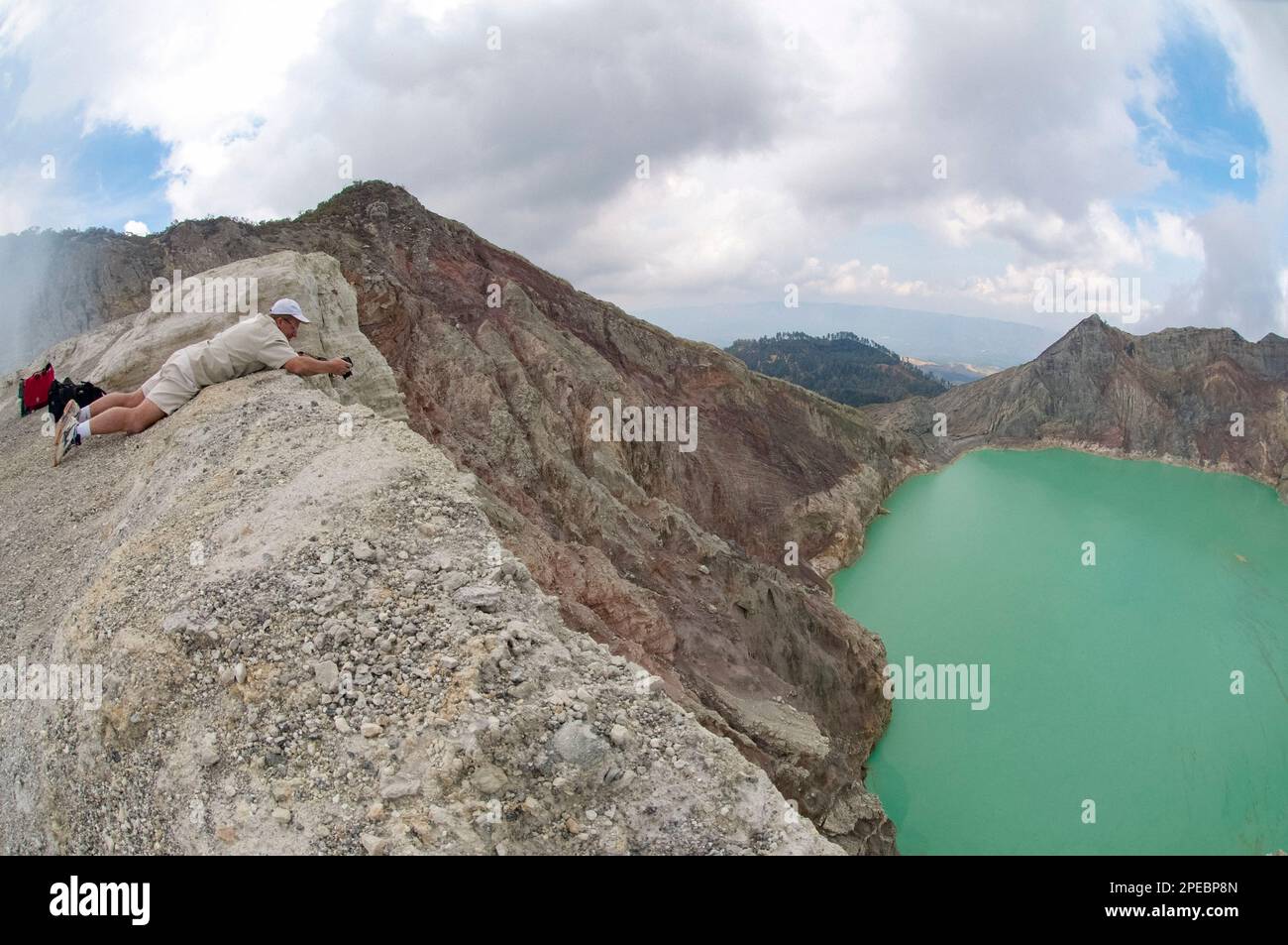 Man (Modell veröffentlicht) mit Blick auf den türkisgrünen See und die Seite des Kraters, Mount Ijen, Ost-Java, Indonesien Stockfoto