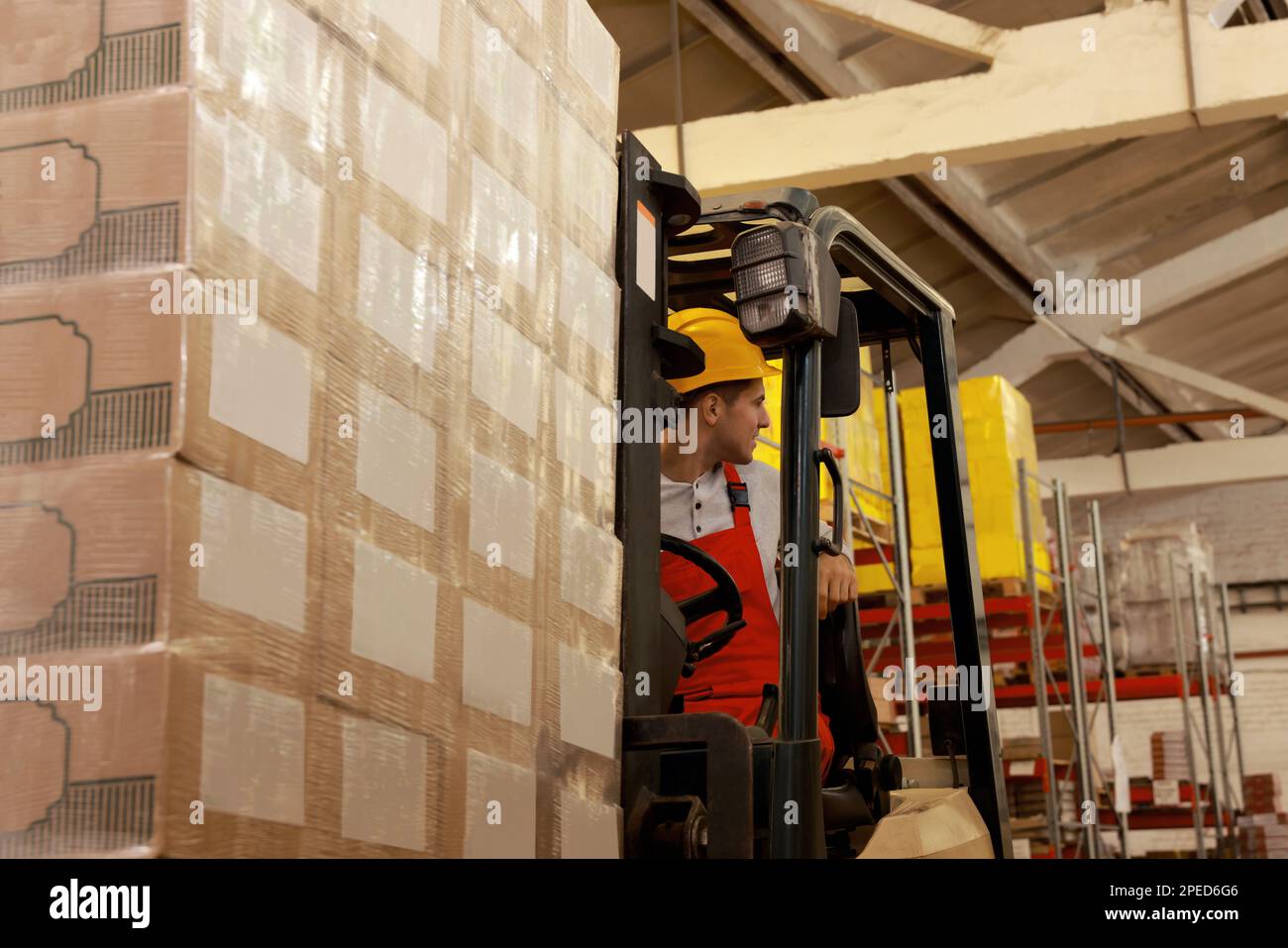 Arbeiter, der Pappkartons mit Gabelstapler im Lager sortiert. Logistikkonzept Stockfoto