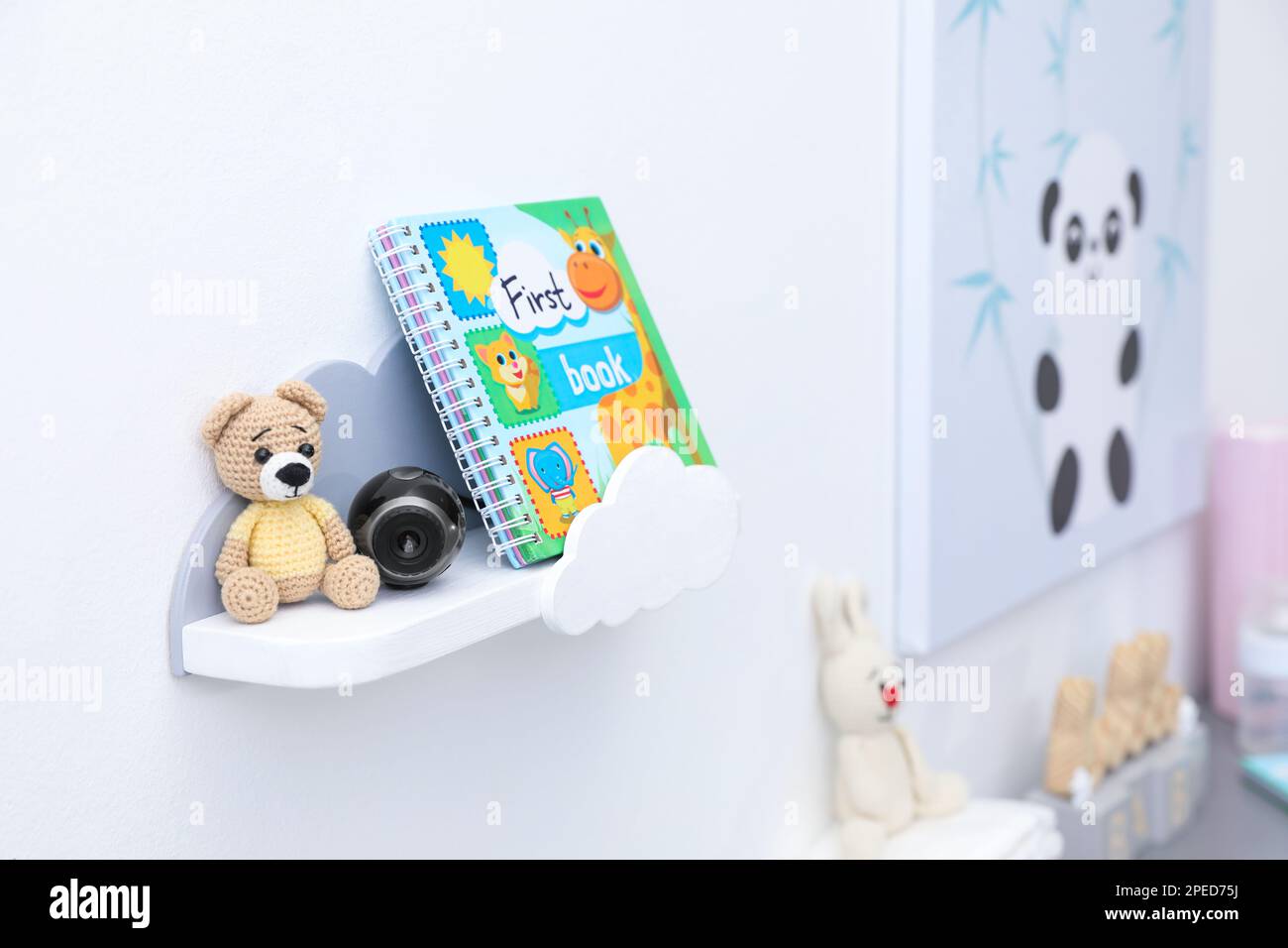 Die kleine Kamera ist zwischen dem Spielzeugbären und dem Buch versteckt und befindet sich im Regal des Kinderzimmers Stockfoto
