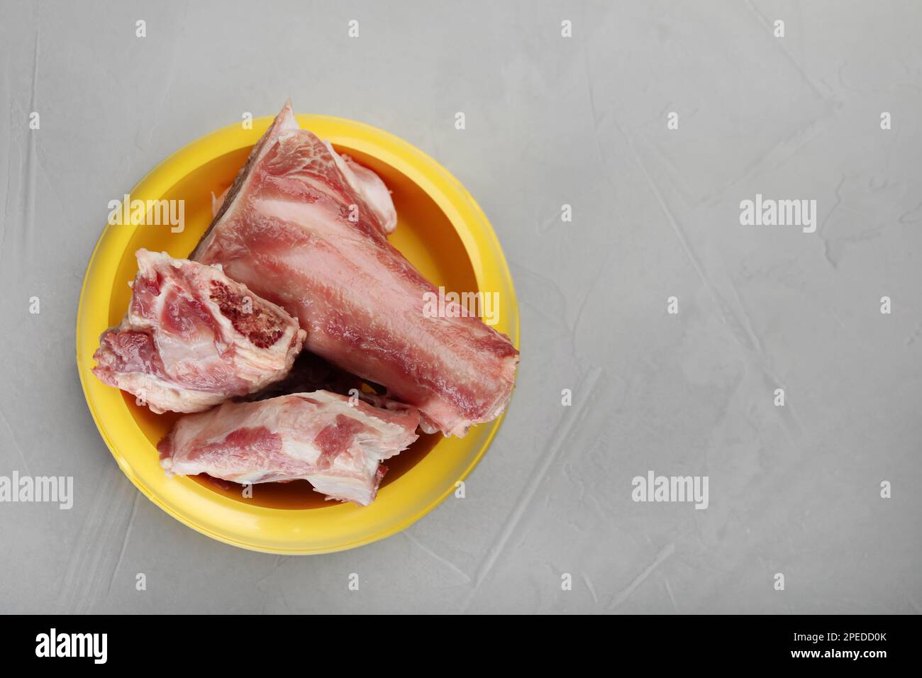 Fütterschüssel mit rohen gehackten Fleischknochen auf grauem Tisch, Draufsicht. Platz für Text Stockfoto