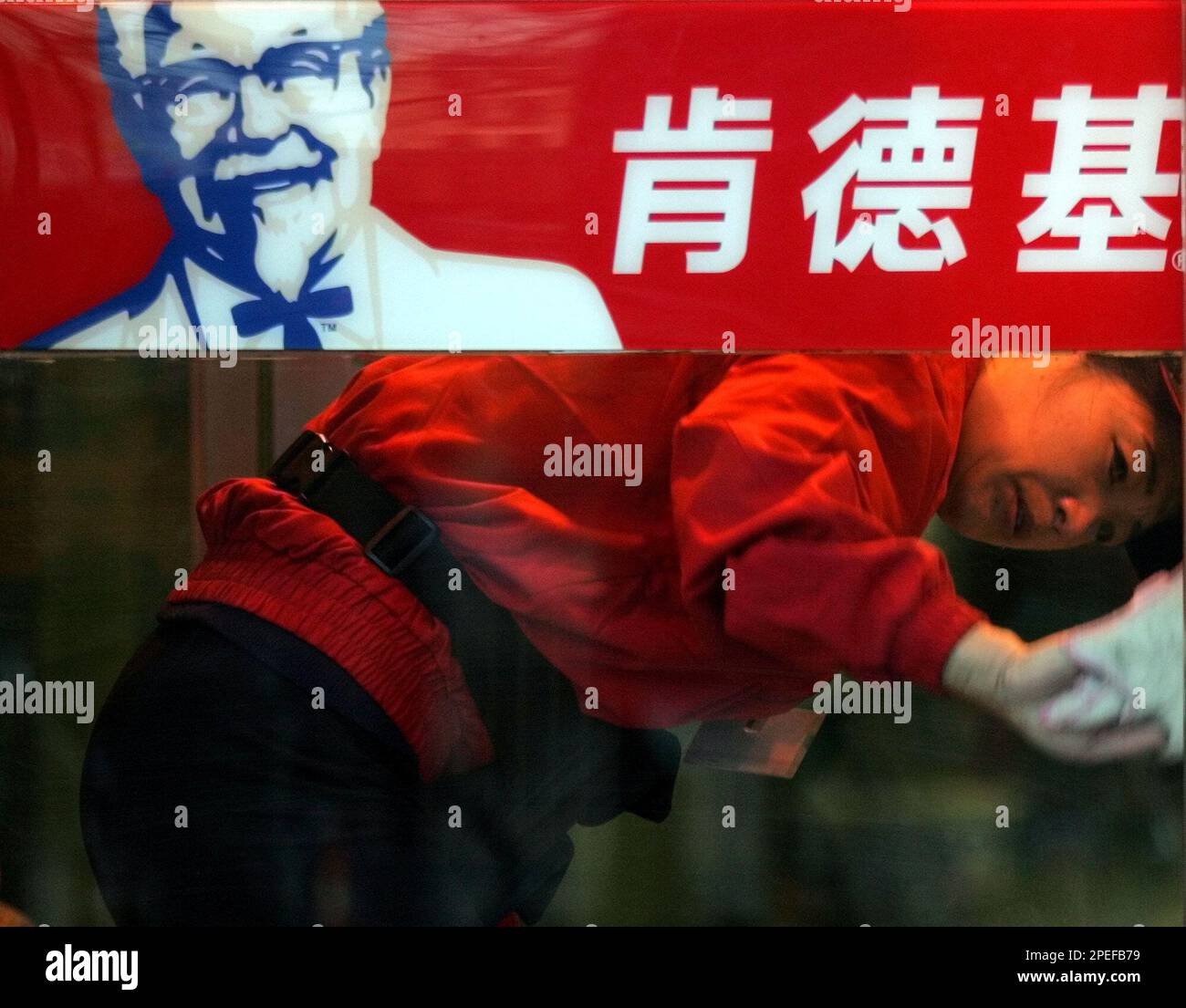 A Chinese worker cleans the glass door of a KFC restaurant in Beijing Tuesday, Jan 18, 2005. China's relentless appetite for the colonel's chicken has KFC on a building boom in the world's most populous country, with 1,200 locations, soaring profits and a menu that mixes in bamboo shoots and lotus roots. (AP Photos/Ng Han Guan) Stockfoto