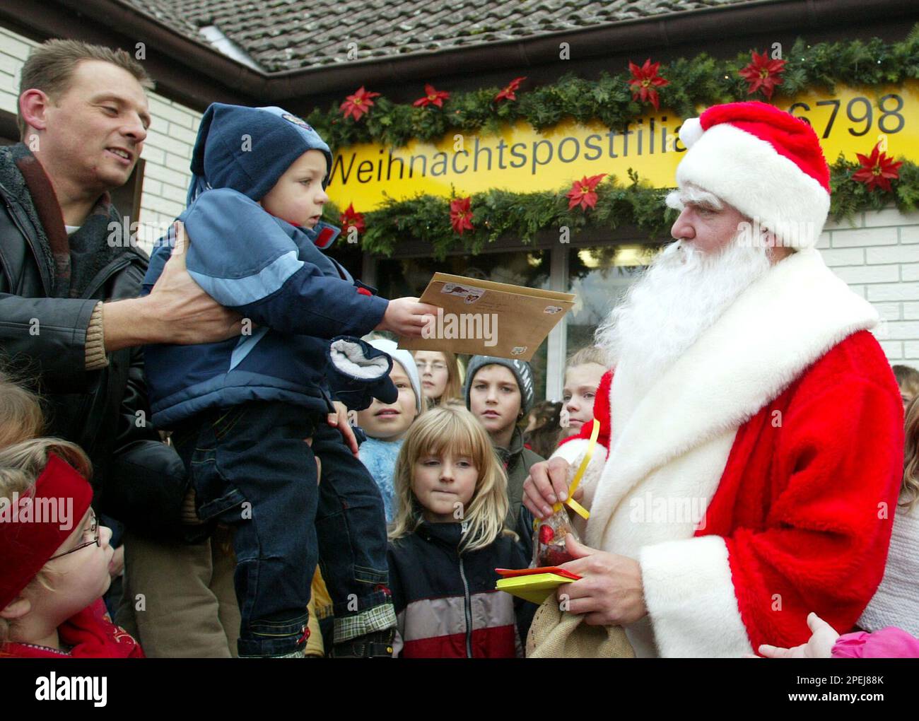 Ein Junge Ueberreicht Dem Weihnachtsmann Einen Wunschzettel Vor Einer 