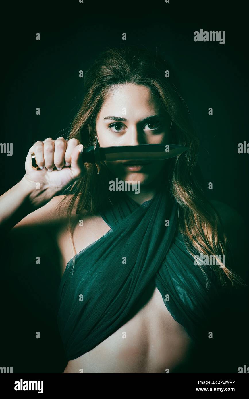 Eine gefährliche, schöne Frau, die ein Messer in der Hand hält Stockfoto