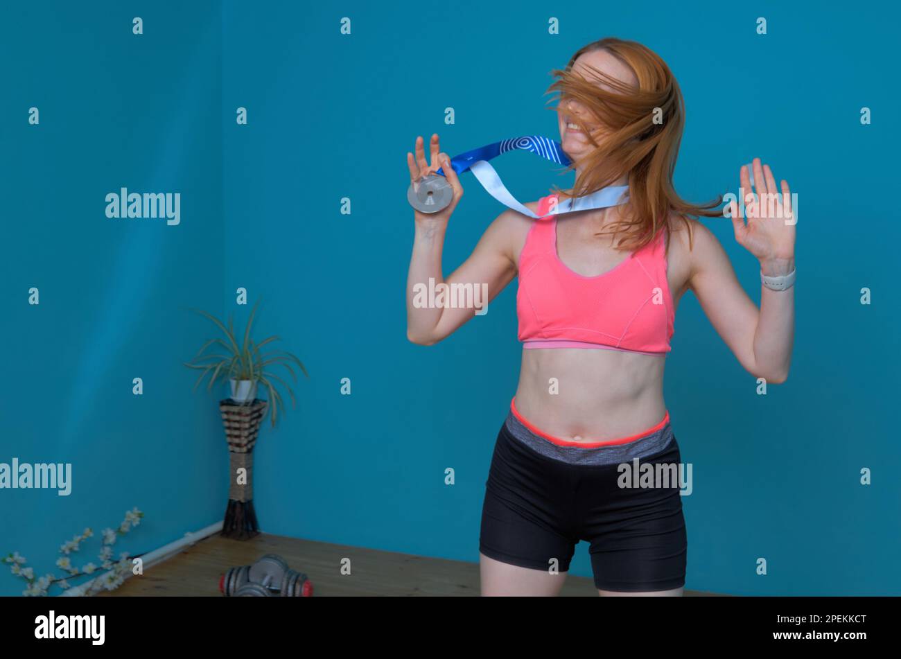 Eine Frau in Sportbekleidung freut sich über eine gewonnene Sportmedaille Stockfoto