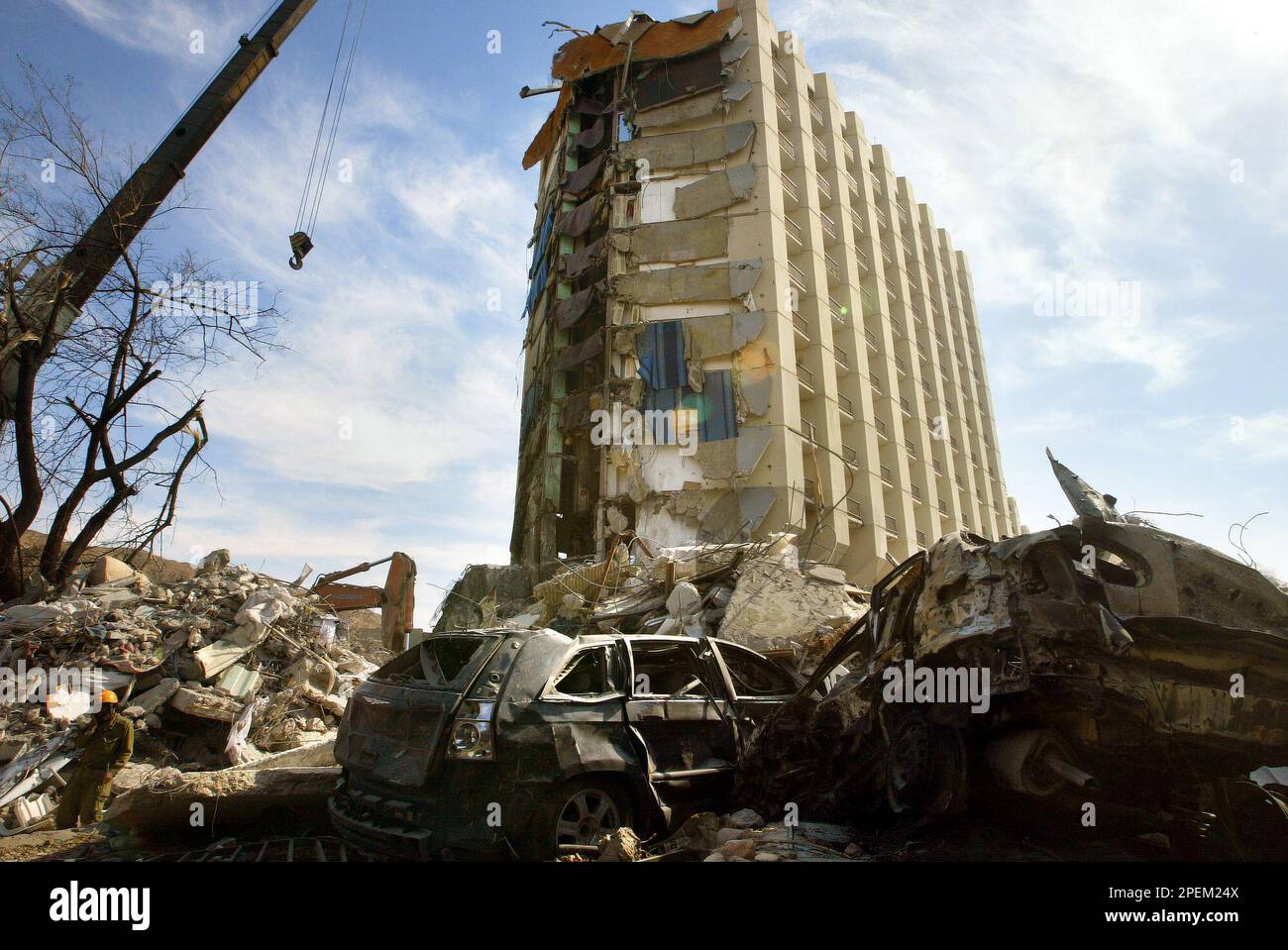 An Israeli army rescuer soldier, left, walks past rubble and destroyed cars in front of the partially-destroyed Taba Hilton hotel, which was car bombed Thursday, in Taba, Egypt, on the border with the southern tip of Israel, Sunday, Oct, 10, 2004. Dozens have been detained on suspicion they supplied explosives for car bomb attacks at two Egyptian resorts that killed at least 33 people, most of them Israelis, Egyptian officials said Saturday. (AP Photo/Brennan Linsley) Stockfoto