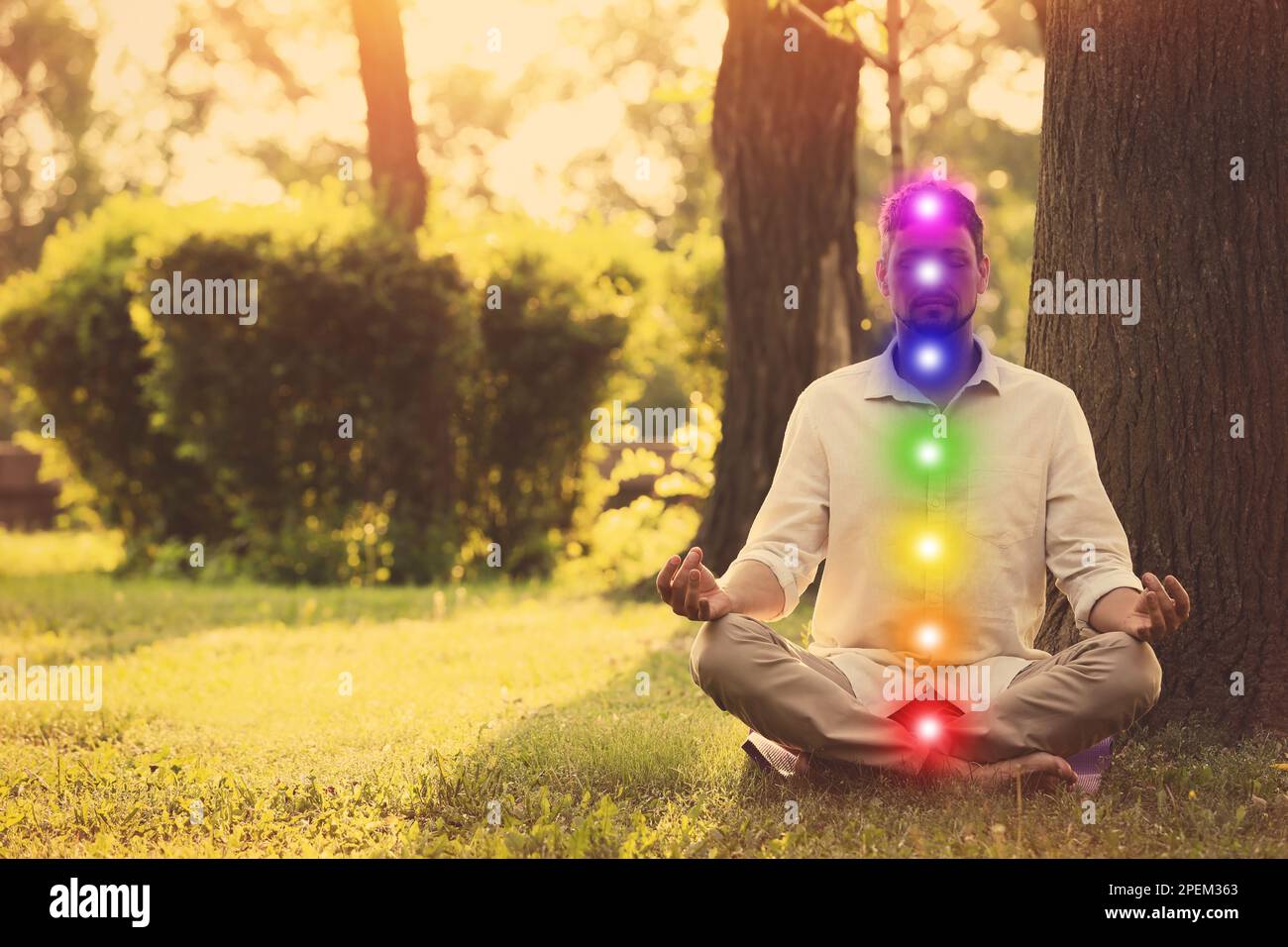 Ein Mann meditiert im Park an einem sonnigen Sommertag. Schema von sieben Chakren, Illustration Stockfoto