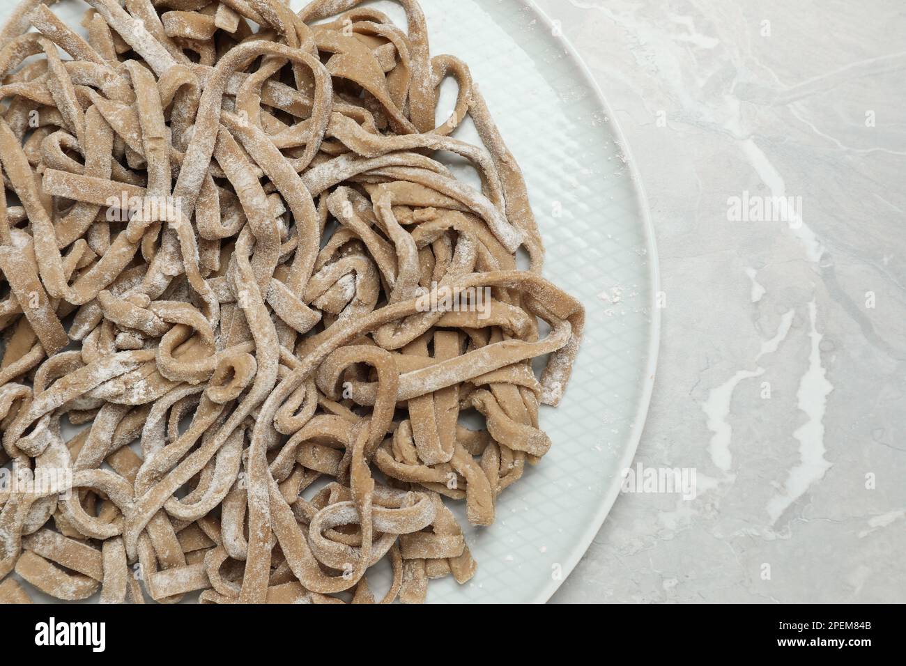 Ungekochter hausgemachter Soba (Buchweizen-Nudeln) auf grauem Tisch, Draufsicht Stockfoto