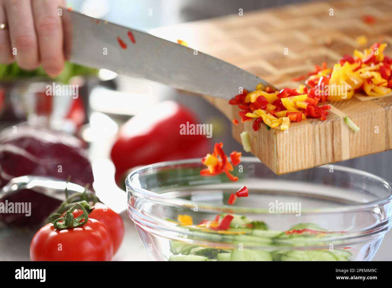 Der Koch gibt gehackten roten gelben Pfeffer zum Salat hinzu Stockfoto