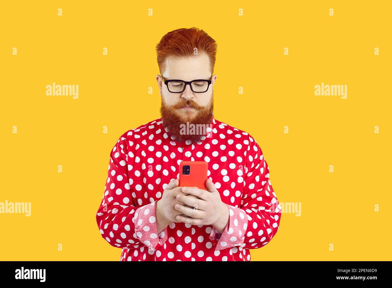 Ein echt lustiger, bärtiger, fetter junger Kerl, der Anrufe oder SMS auf dem Handy macht Stockfoto