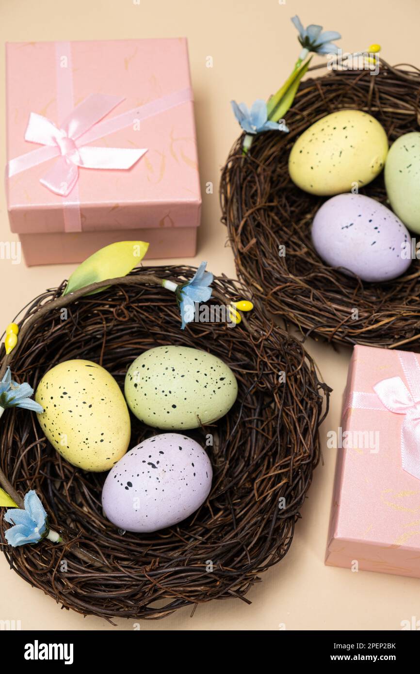 Geschenke zu Ostern, Osterverkauf. Eier in Nestern und Geschenkschachteln auf beigefarbenem Hintergrund. Stockfoto