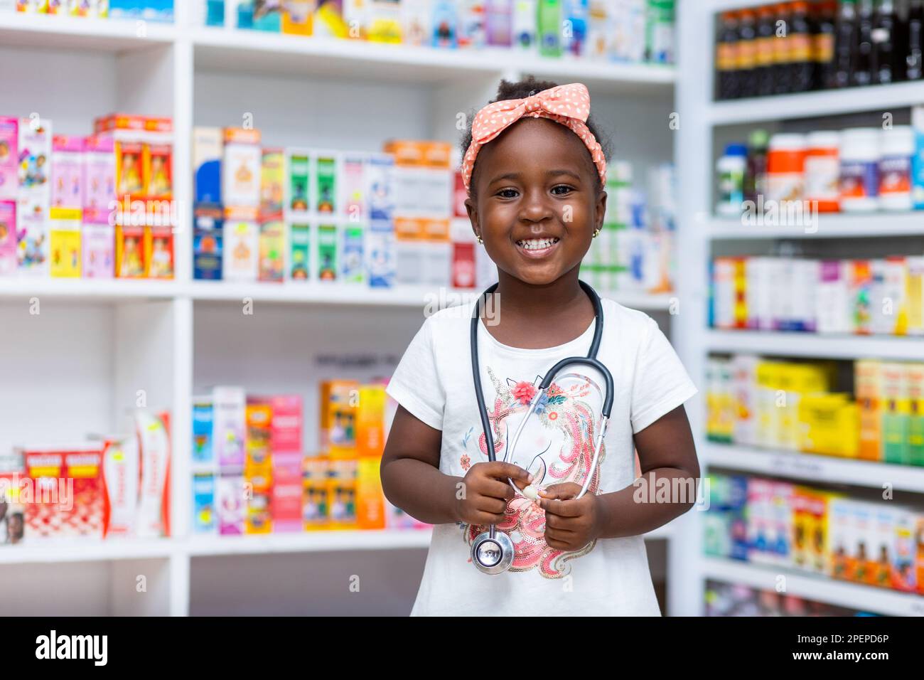 Porträt eines schwarzafrikanischen Mädchens Kind in einer Apotheke mit Stethoskop, träumt davon, in Zukunft Arzt zu werden. Stockfoto