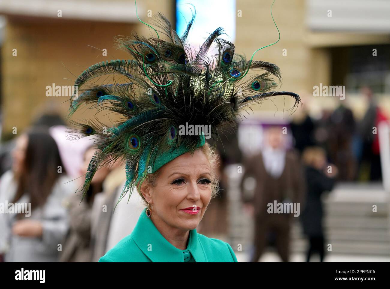 Ein Rennfahrer, der einen Pfauenfederfaszinator trägt, kommt vor dem dritten Tag des Cheltenham Festivals auf der Cheltenham Racecourse an. Foto: Donnerstag, 16. März 2023. Stockfoto