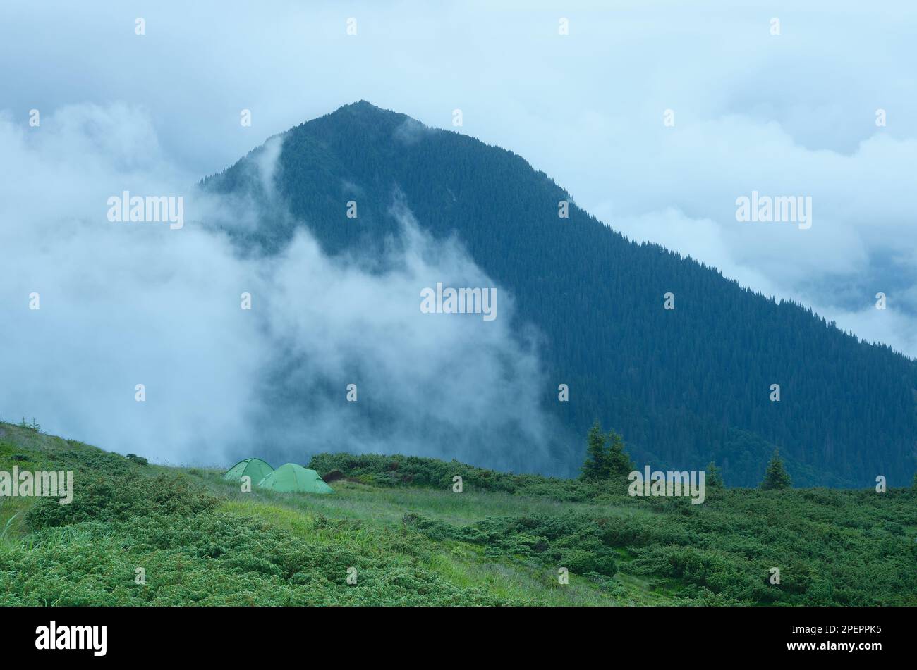 Berglandschaft mit Camping. Touristenzelt auf einem Hügel. In den Wolken montieren. Schönheit in der Natur Stockfoto