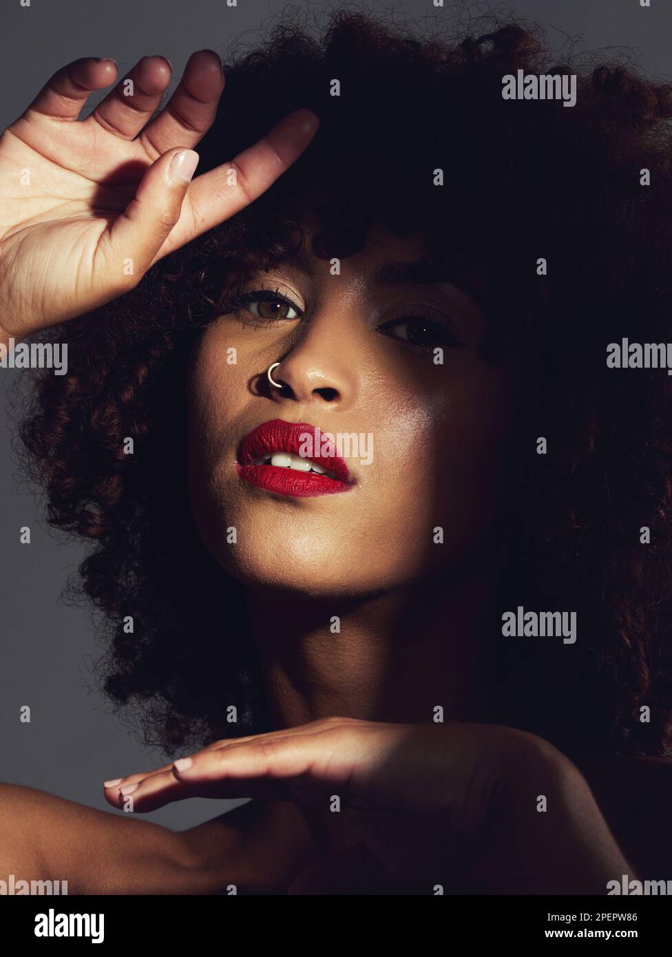 Rote Lippenstift, Schatten und Make-up auf schwarzer Frau mit Schönheit, Afro oder natürlichem Haar im Studio. Das Gesicht eines ästhetischen weiblichen Modells mit einer glühenden, glänzenden und Stockfoto