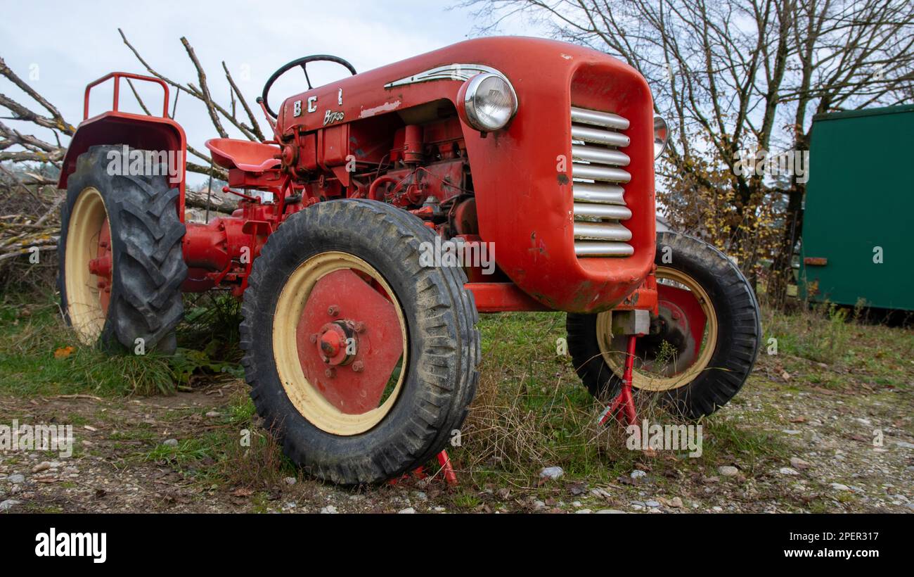 Ein Bild eines klassischen roten Traktors auf einem Feld neben einem Grenzzaun Stockfoto
