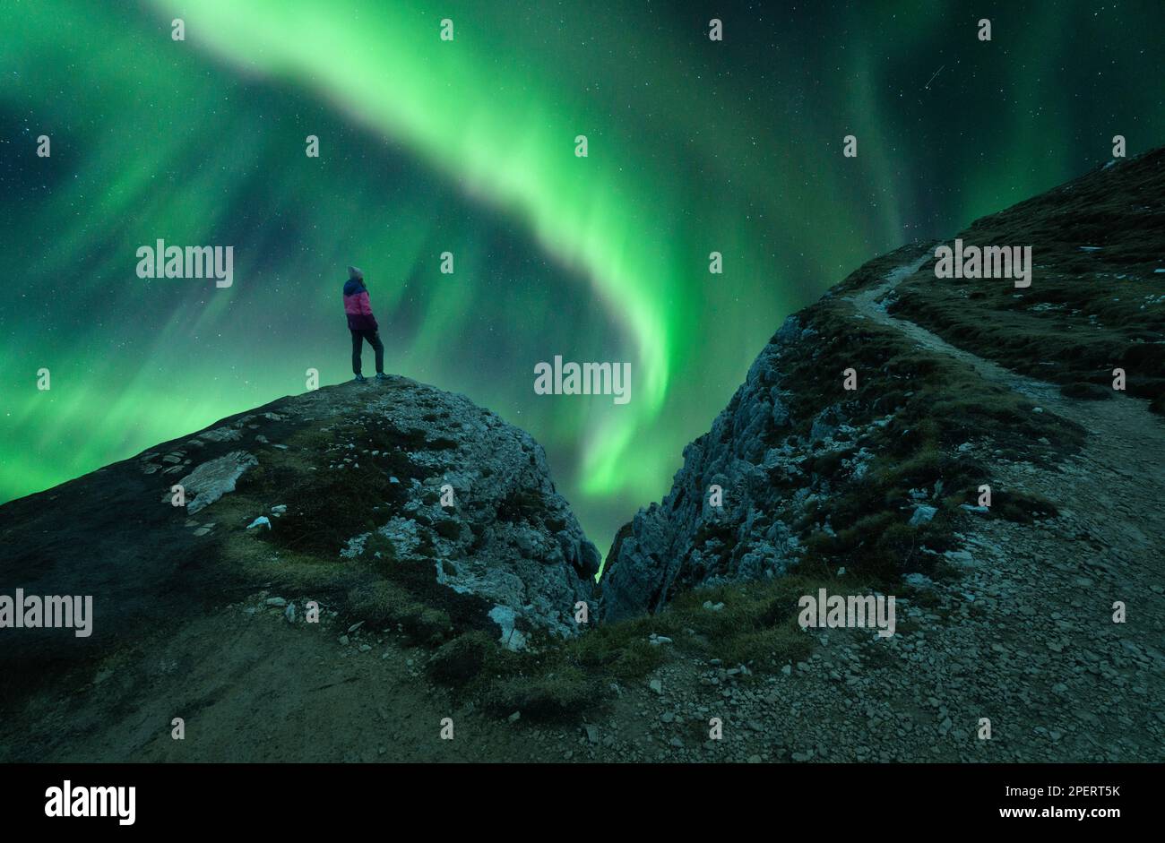 Nordlichter und junge Frau auf Berggipfel bei Nacht. Auror Stockfoto