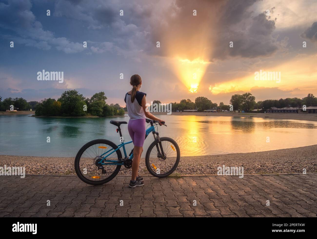 Frau auf dem Mountainbike in der Nähe des Sees bei Sonnenuntergang im Sommer Stockfoto