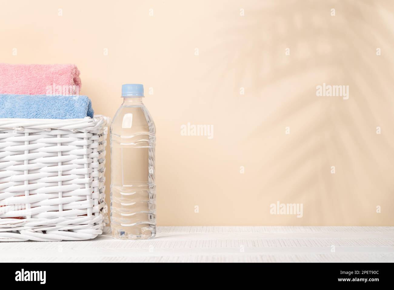 Wasserflasche und Badhandtücher auf dem Tisch mit Platz für Ihr Produkt oder Text. Spa-Arrangement Stockfoto