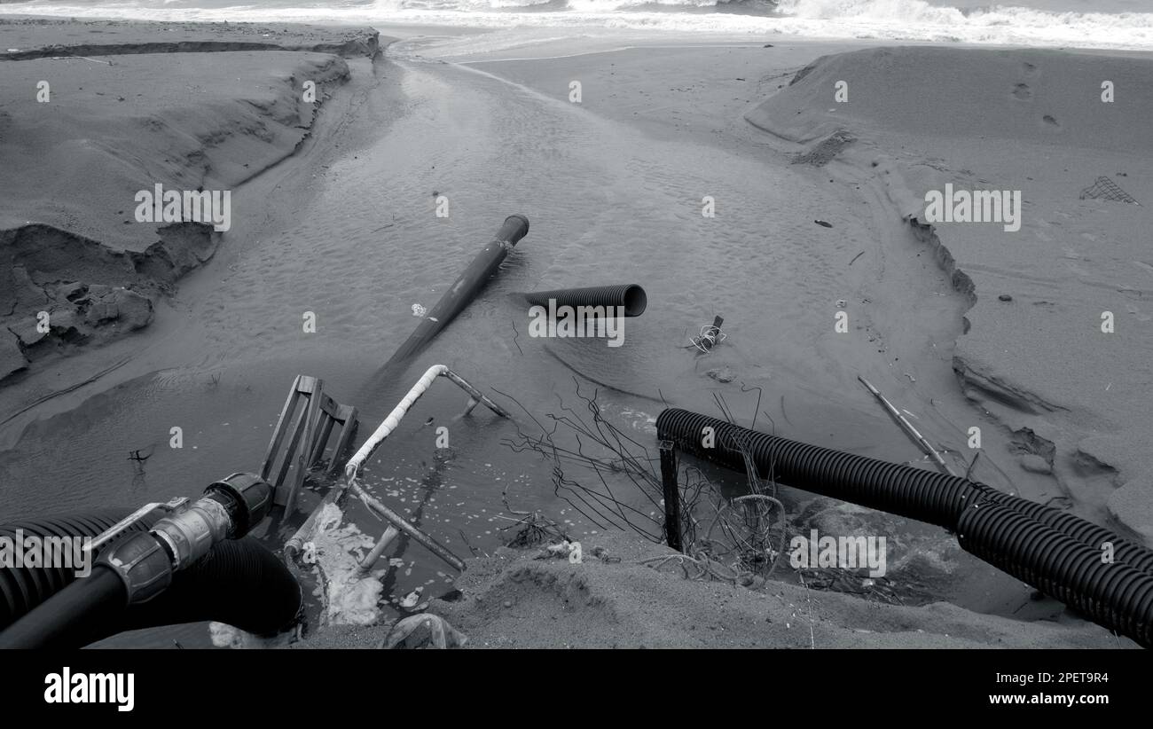 Industrielles Abwasser, die Pipeline leitet flüssigen Industrieabfall an einem Stadtstrand ins Meer. Verschmutztes Abwasser strömt aus einem Kunststoffkanalrohr auf Stockfoto