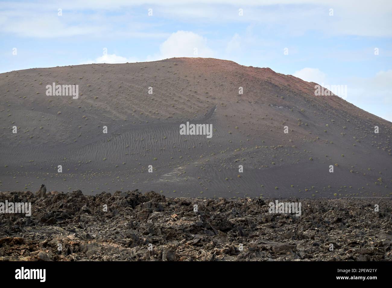 Blick über vulkanische Bomben, vulkanische Felsformationen und Lavafelder zu fernen Vulkanen bedeckt mit Pikon- und ascheparque nacional de timanfaya Lanzaro Stockfoto