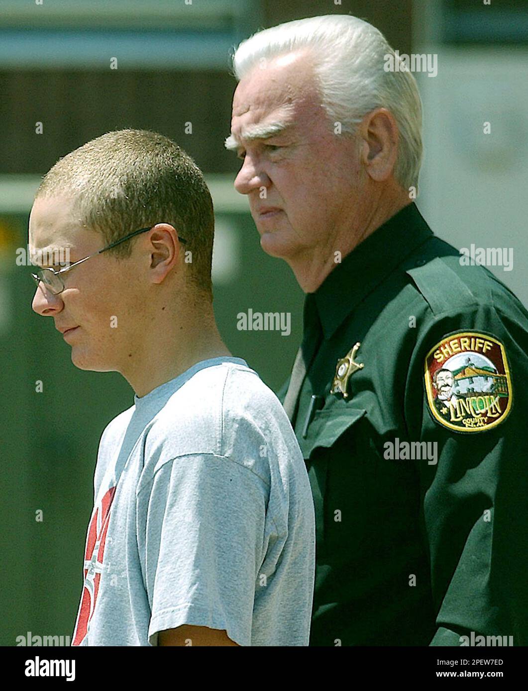 Cody Posey, left, is led out of the Otero County Courthouse by Lincoln County Sheriff's Department transport officer Bill Webster, right, following a hearing Friday, July 9, 2004, in Alamogordo, N.M. Posey, the 14-year-old boy accused of killing his family at newsman Sam Donaldson's ranch, appeared in Children's Court Friday and denied the charges. (AP Photo/Alamogordo Daily News, Ellis Neel). Stockfoto