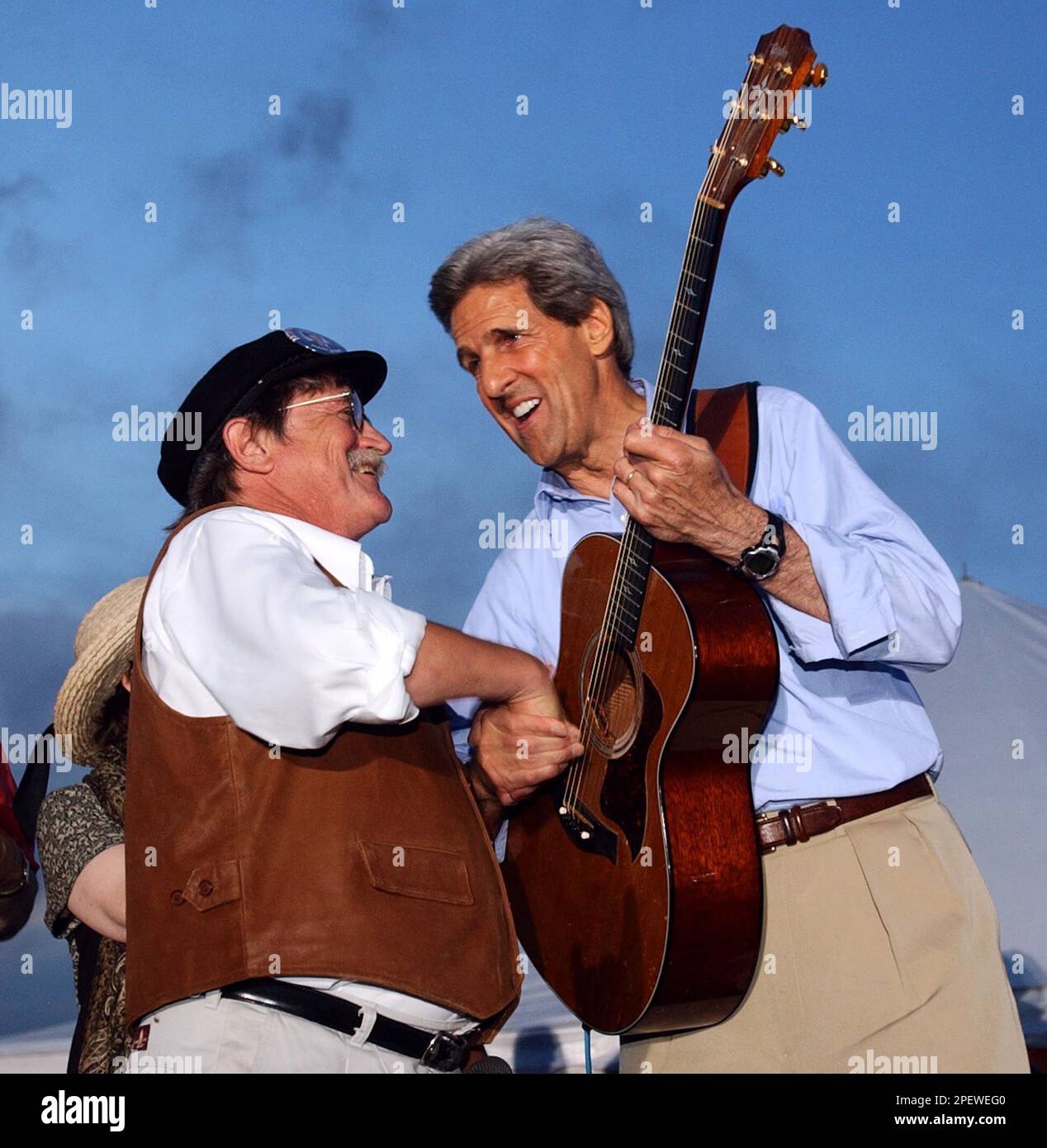 Democratic Presidential hopeful Sen. John Kerry, D-Mass., shakes hands with Warren Nelson after playing guitar with his Big Top Chautauqua Band during a rally at the Evergreen Stock Farm in Bloomer, Wisc. Friday, July 2, 2004. Kerry is on a three day bus campaign trip through Wisconsin, Minnesota and Iowa. (AP Photo/Gerald Herbert) Stockfoto