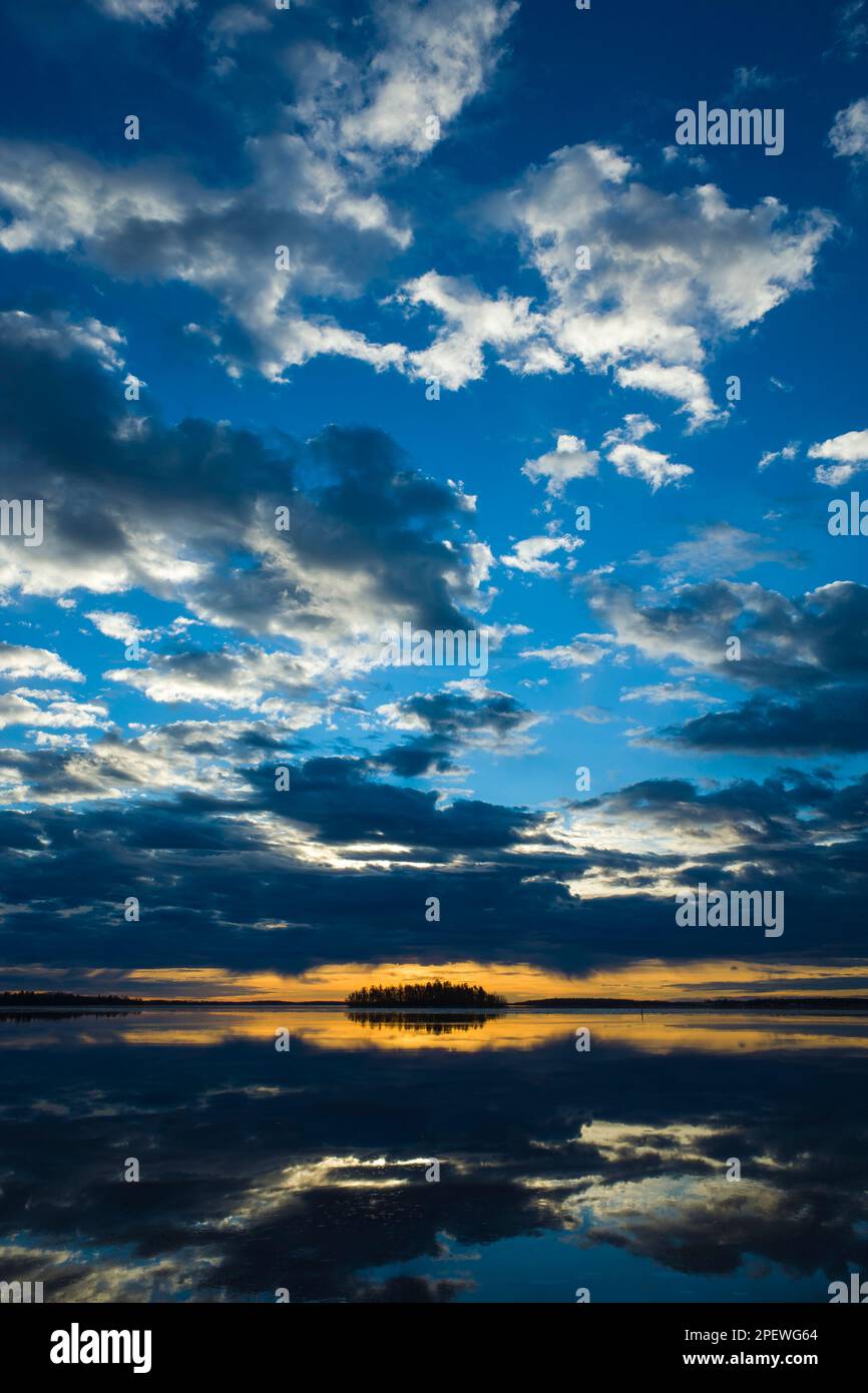 Erstaunlich schöner Sonnenaufgang über dem Malarsee in Schweden, ruhiges Wasser reflektiert den Himmel mit dramatischen Wolken, die von der Sonne beleuchtet werden, hellgelber Horizont mit d Stockfoto