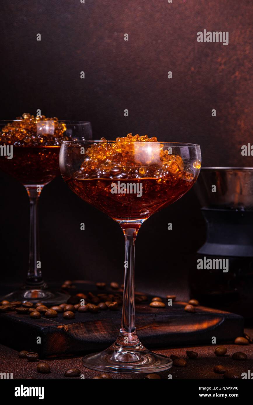 Espresso-Kaffee-Slush-Cocktail in martini-Glas, mit handgefertigter Kaffeepadmaschine. Harter Kaffee Granita, auf dunkelbraunem Hintergrund Kopierbereich Stockfoto