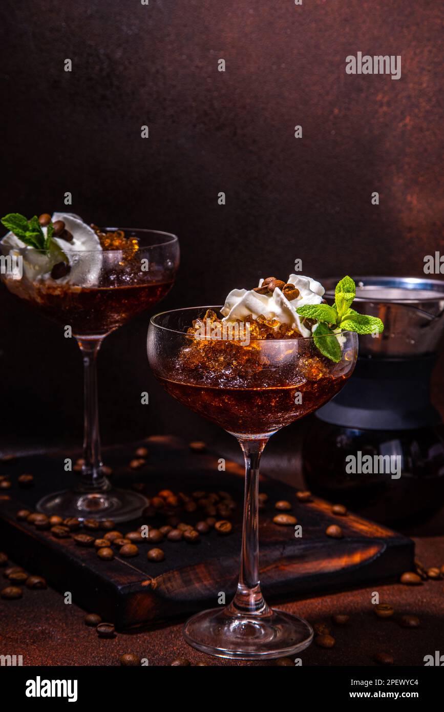 Espresso-Kaffee-Slush-Cocktail in martini-Glas, mit handgefertigter Kaffeepadmaschine. Harter Kaffee Granita, auf dunkelbraunem Hintergrund Kopierbereich Stockfoto