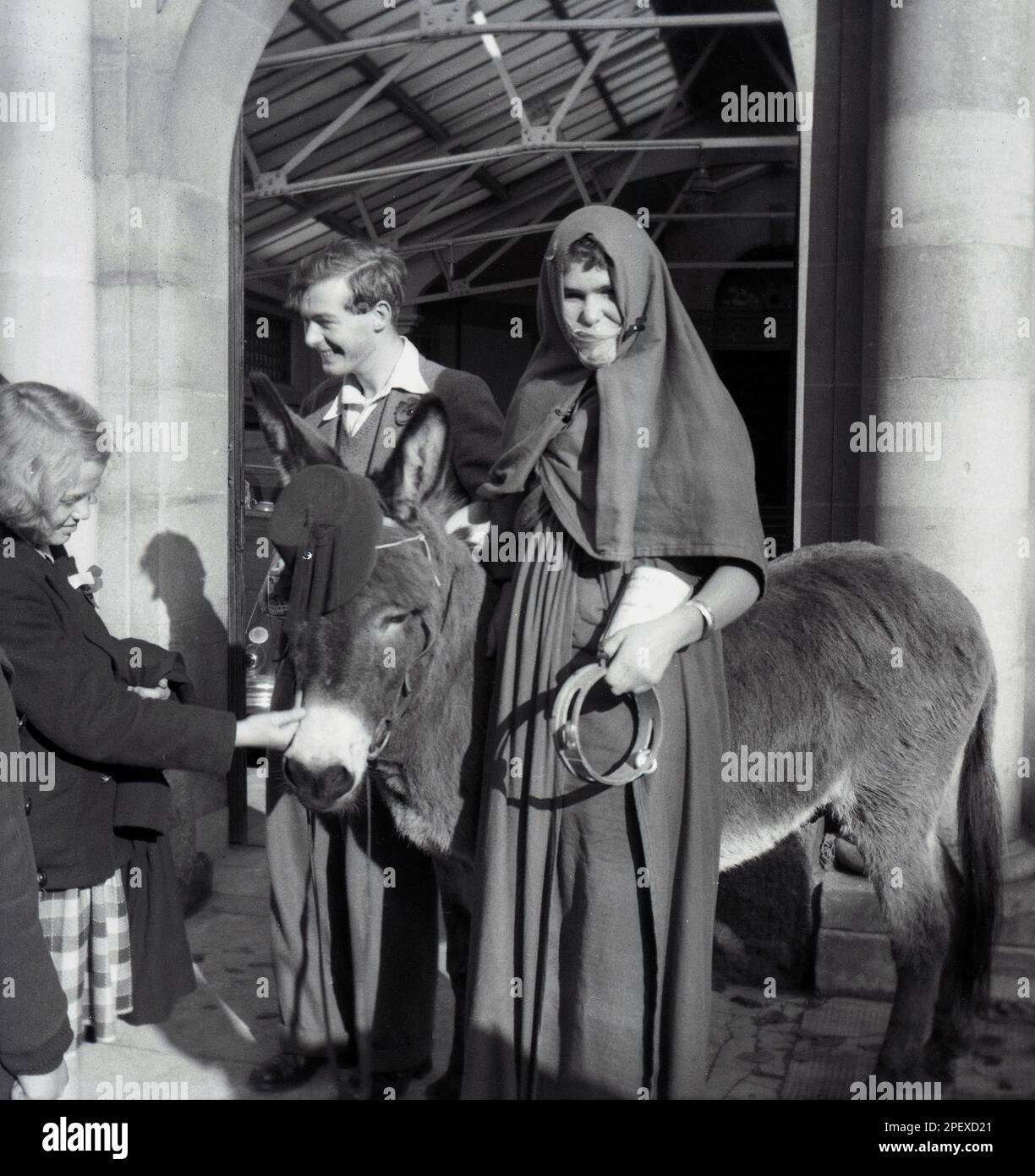 1955, Historica, Rag Week, zwei männliche Studenten, einer als Araber verkleidet, mit einem Esel, Cambridge University, England, Großbritannien. In Großbritannien war die RAG Week eine Handelszeit an Universitäten und Hochschulen, in der verschiedene Veranstaltungen von Studenten organisiert werden, um Geld für wohltätige Zwecke zu sammeln. Eine Prozession durch die lokale Stadt mit dekorierten Wagen war oft das Hauptereignis der Lumpen-Feier, ein Begriff, der aus dem Verb „to rag“ abgeleitet sein soll, was „pester“ bedeutet, wo die Studenten „zerfleischt“ oder Menschen ermutigt haben, für wohltätige Zwecke zu spenden. Stockfoto